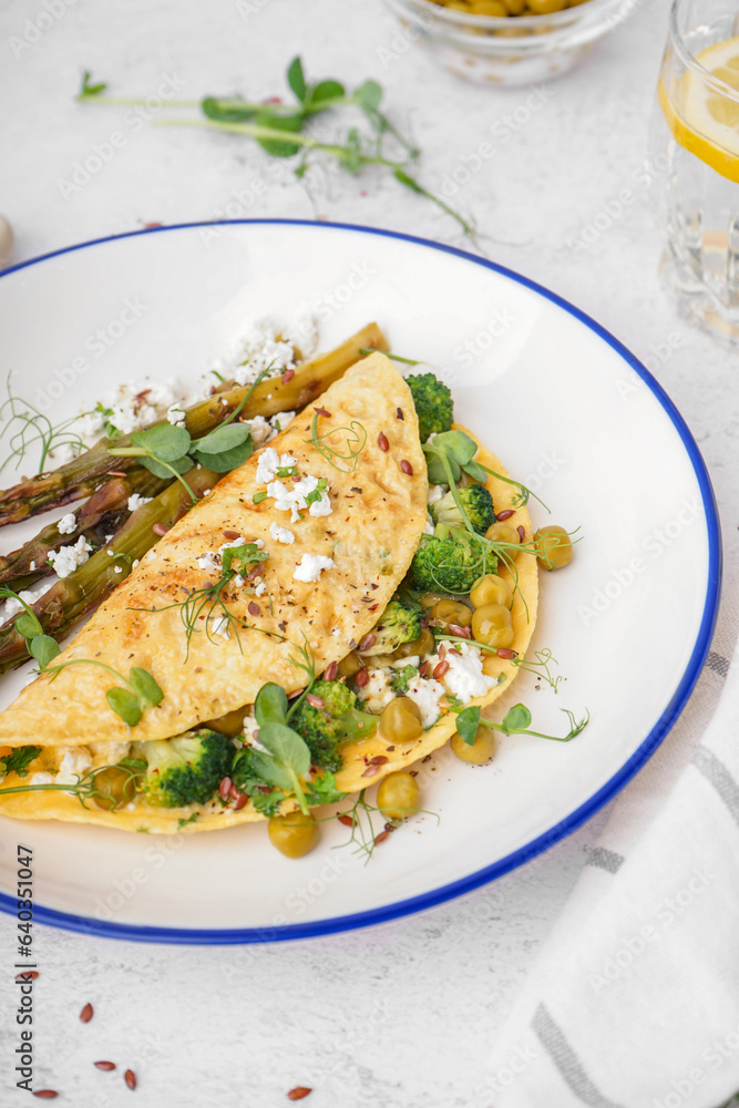 Tasty omelet with broccoli, asparagus and pea on light table