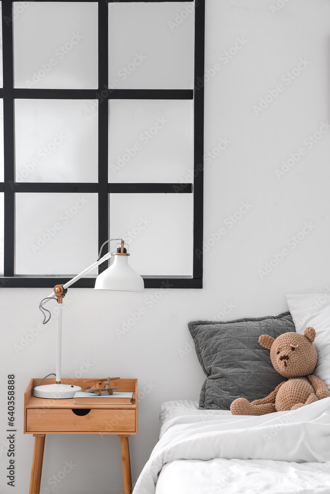 Interior of childrens bedroom with cozy bed, teddy bear and bedside table