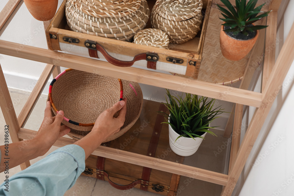 Woman decorating shelving unit with wicker baskets, closeup