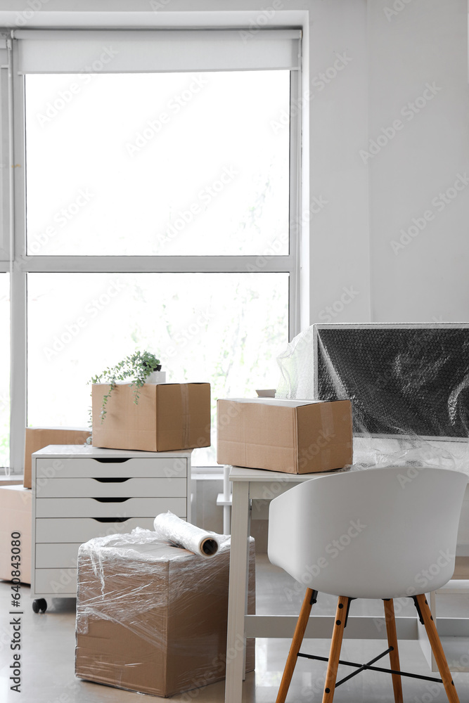 Interior of light office with cardboard boxes and stretch film on moving day
