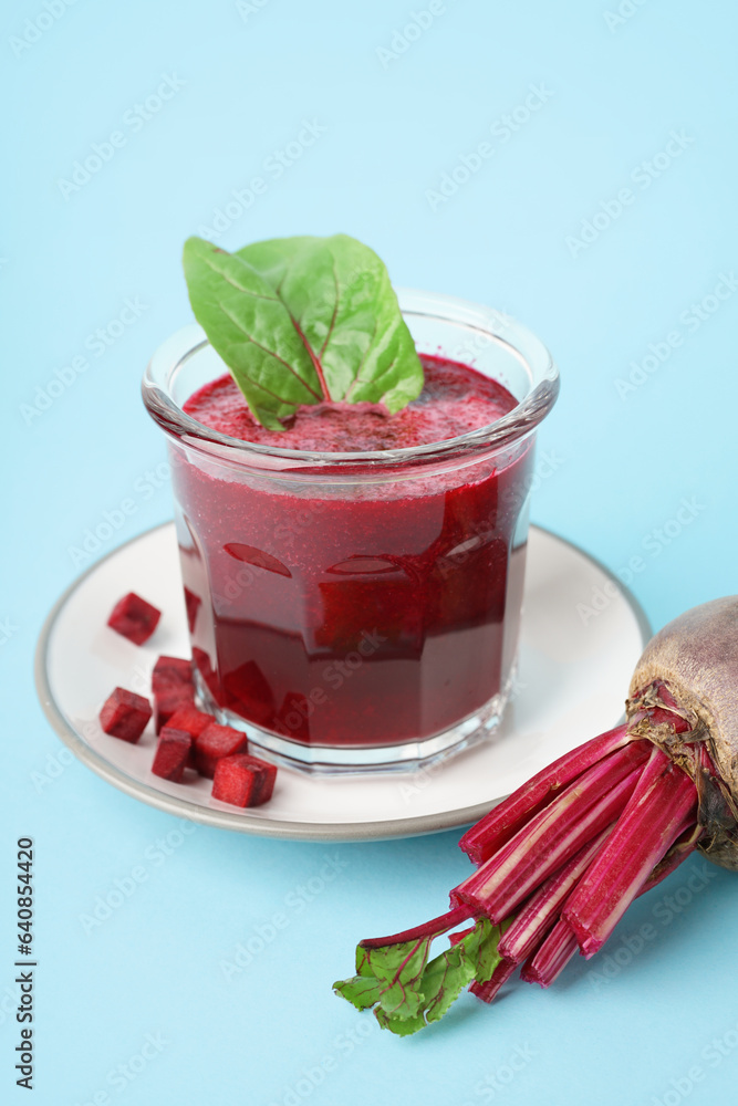 Plate with glass of healthy beet juice and spinach on blue background