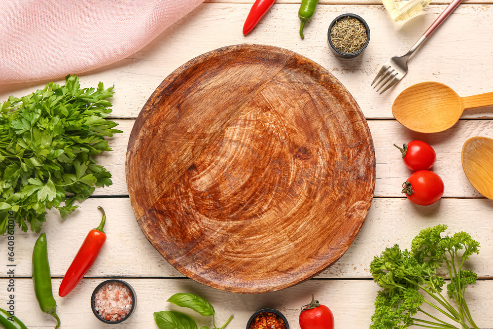 Composition with kitchen board, spices, vegetables and herbs on light wooden background