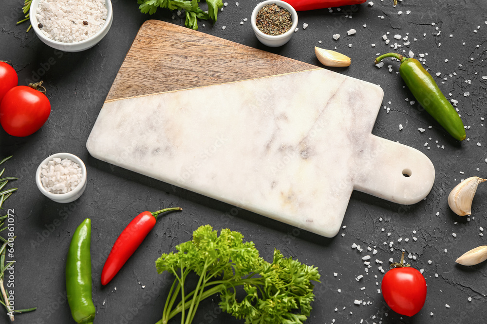 Composition with cutting board, herbs, vegetables and spices on dark background