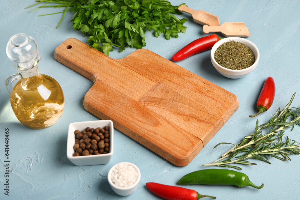 Composition with wooden cutting board, fresh herbs and spices on color background