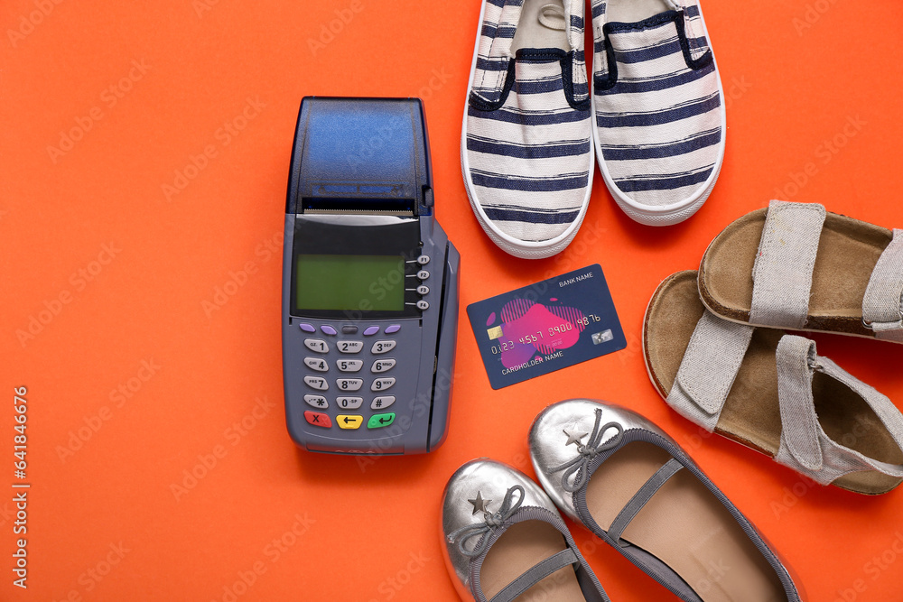 Composition with payment terminal, credit card and different childs shoes on color background
