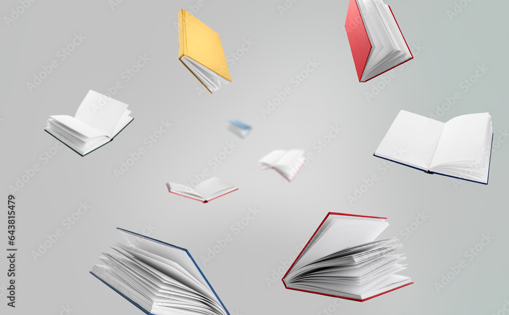 Many flying books on grey background