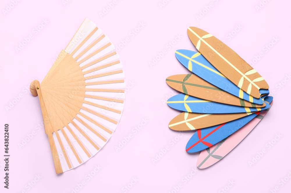 Different mini surfboards and fan on pink background