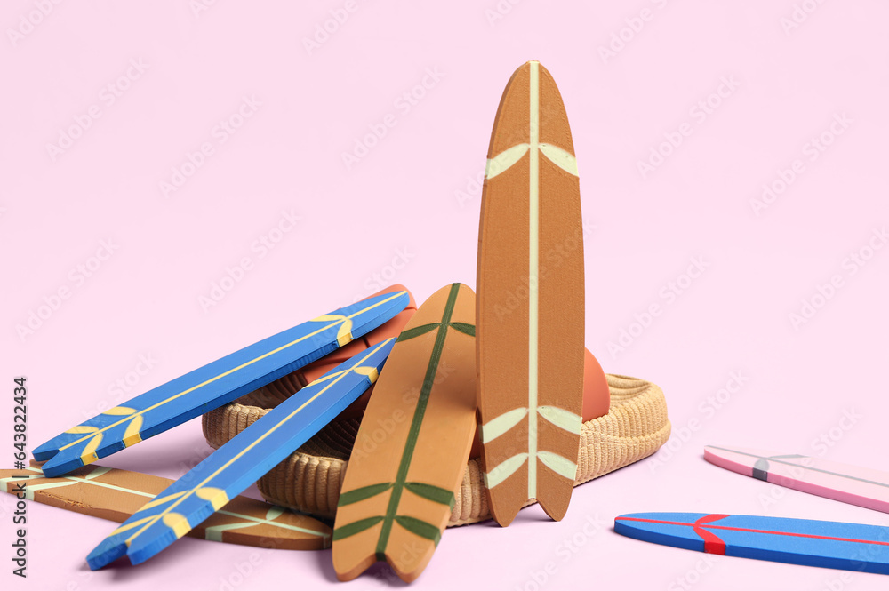 Different mini surfboards and stylish shoes on pink background