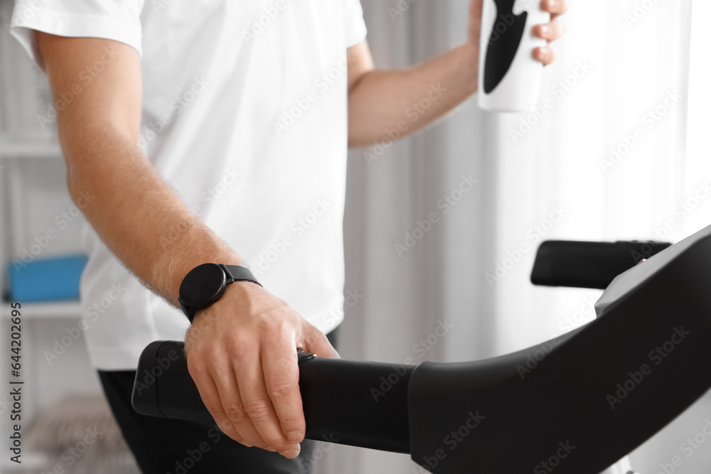 Sporty young man training on treadmill at home, closeup