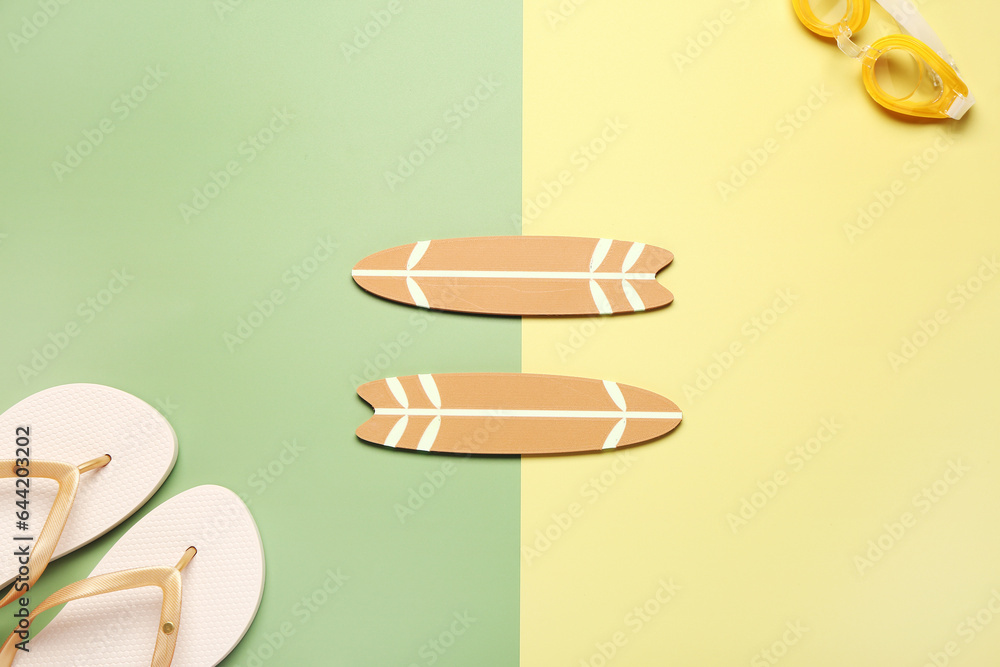 Mini surfboards, flip-flops and goggles on color background