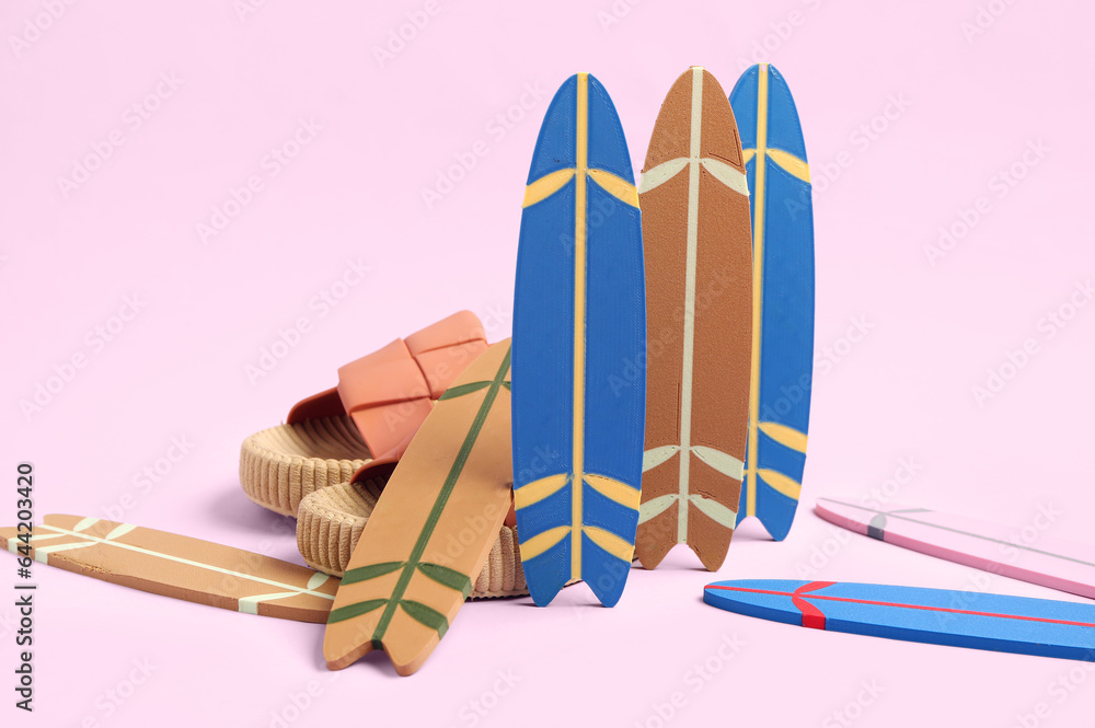 Different mini surfboards and stylish shoes on pink background