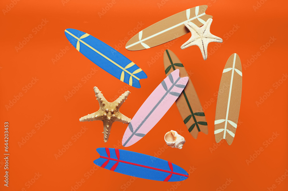 Flying mini surfboards, seashell and starfishes on orange background
