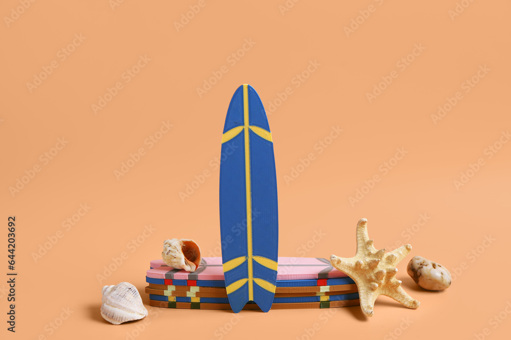Different mini surfboards, stone, seashells and starfish on orange background