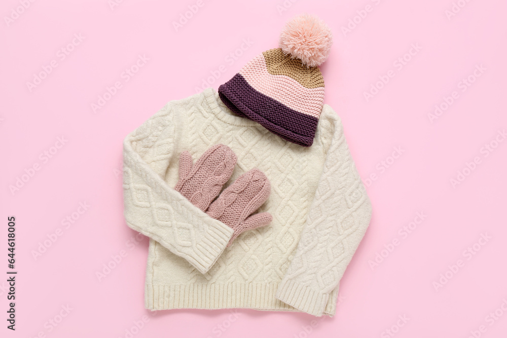 Stylish childrens sweater, warm hat and mittens on pink background