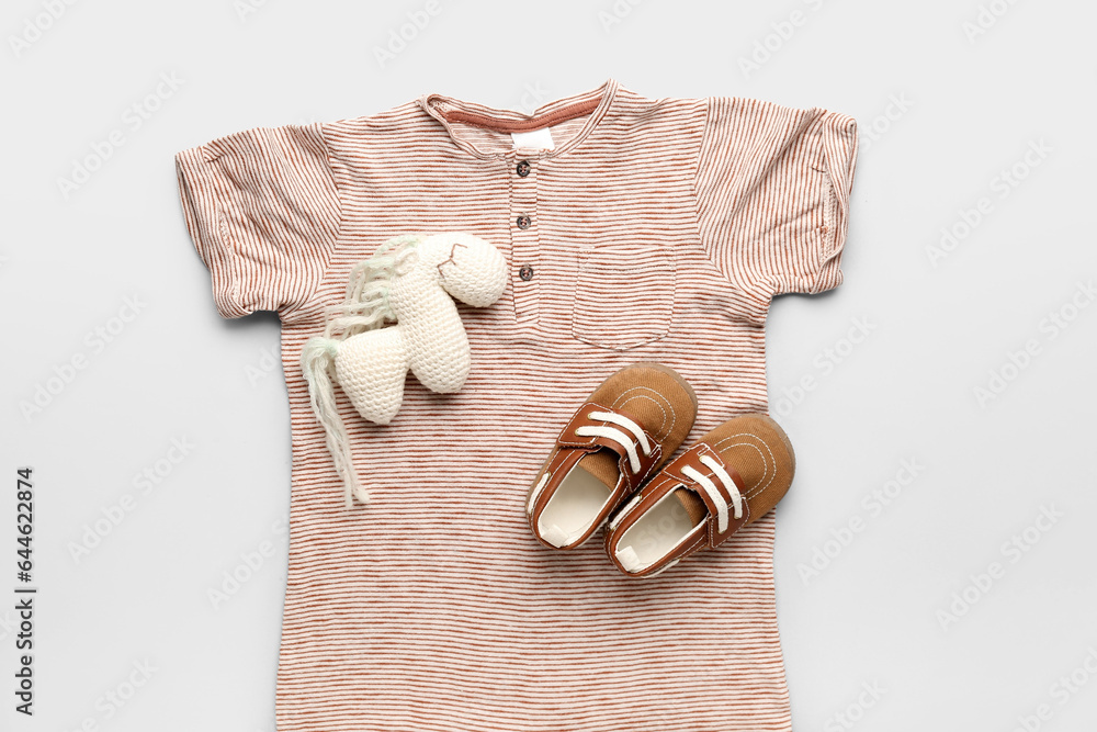 Stylish baby clothes, toy and booties on light background