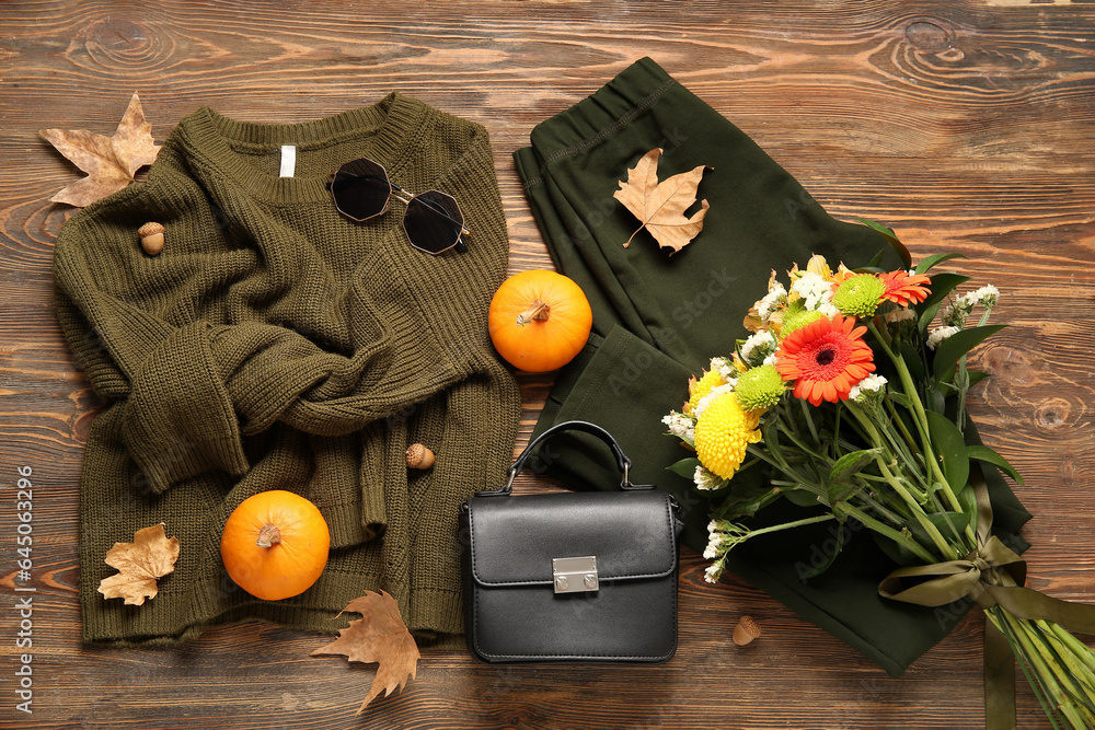 Beautiful autumn composition with stylish clothes, leaves, pumpkins and bouquet of flowers on wooden