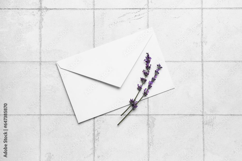 Branches of beautiful lavender flowers and envelope on light tile background