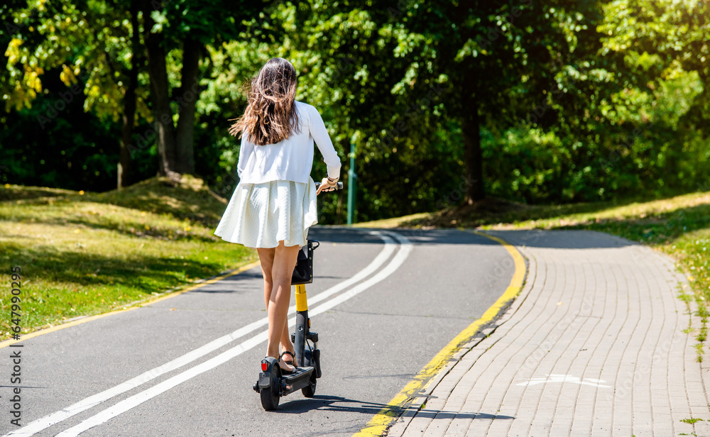 Girl rides an electric scooter in the summer Park 