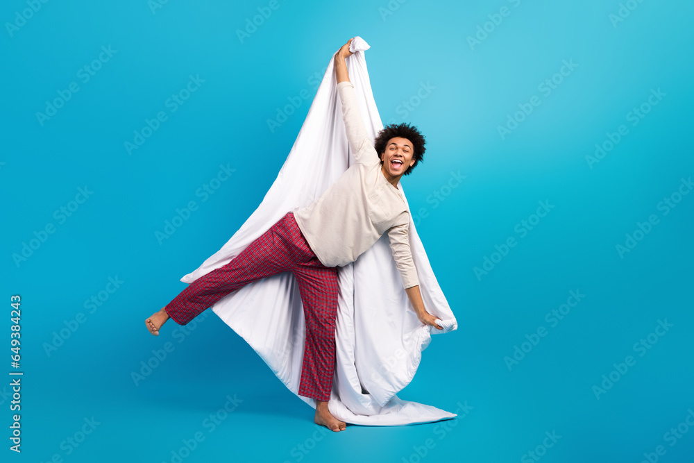 Full size portrait of energetic positive barefoot person hands hold white blanket stand one leg isolated on blue color background