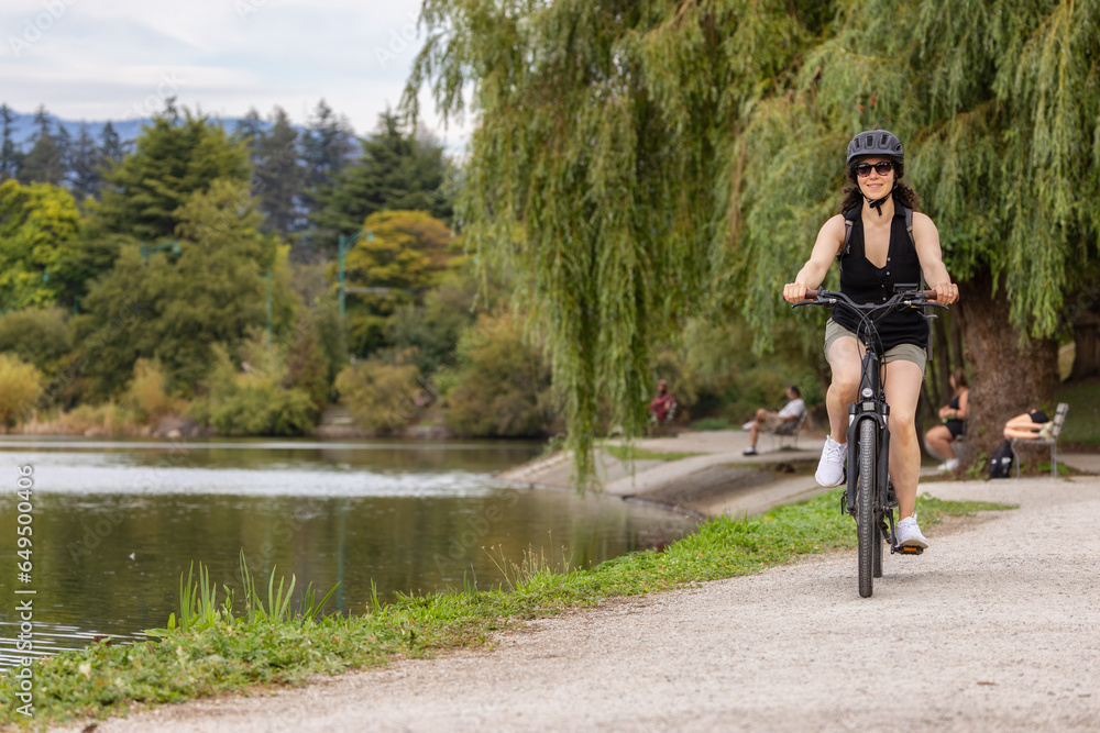 Fit Caucasian Woman riding an Electric Bicycle on a trail in Stanley Park, Downtown Vancouver, British Columbia, Canada