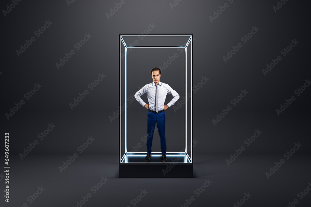Young european businessman standing inside creative glass showcase on light background. Isolation concept.