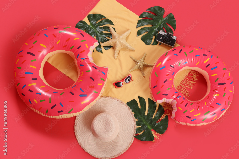 Inflatable rings with beach accessories on red background