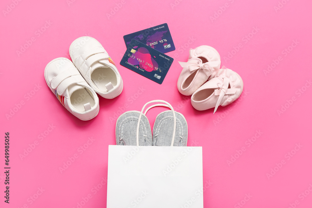 Composition with shopping bag, baby booties and credit cards on pink background