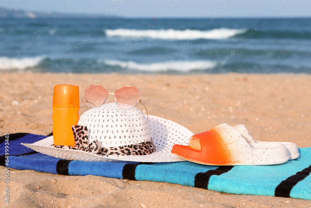Towel with different beach accessories on sand