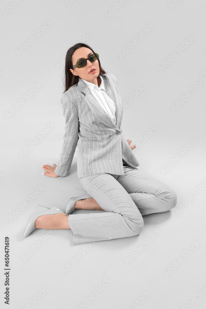 Young woman in stylish suit on light background