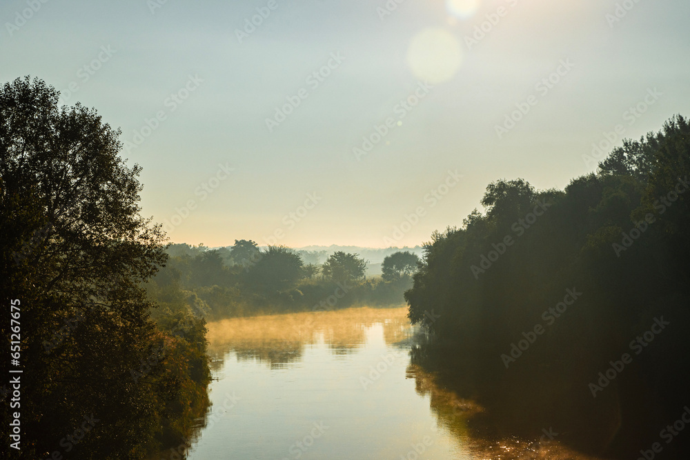 Autumn mist over the river is a magical sight to behold. The river flows silently through the landscape, its surface shrouded in a thin layer of mist. The mist dances and swirls in the gentle breeze.