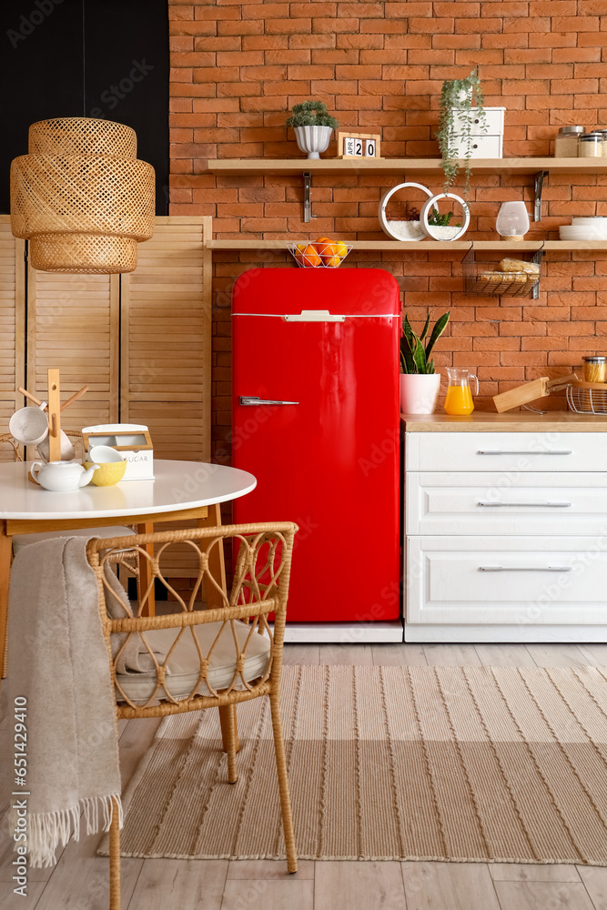 Interior of kitchen with red fridge, counters, shelves, table and lamp