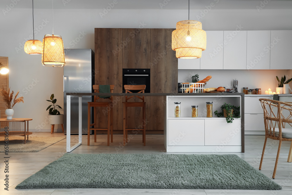 Interior of modern kitchen with stylish island table and glowing lamps
