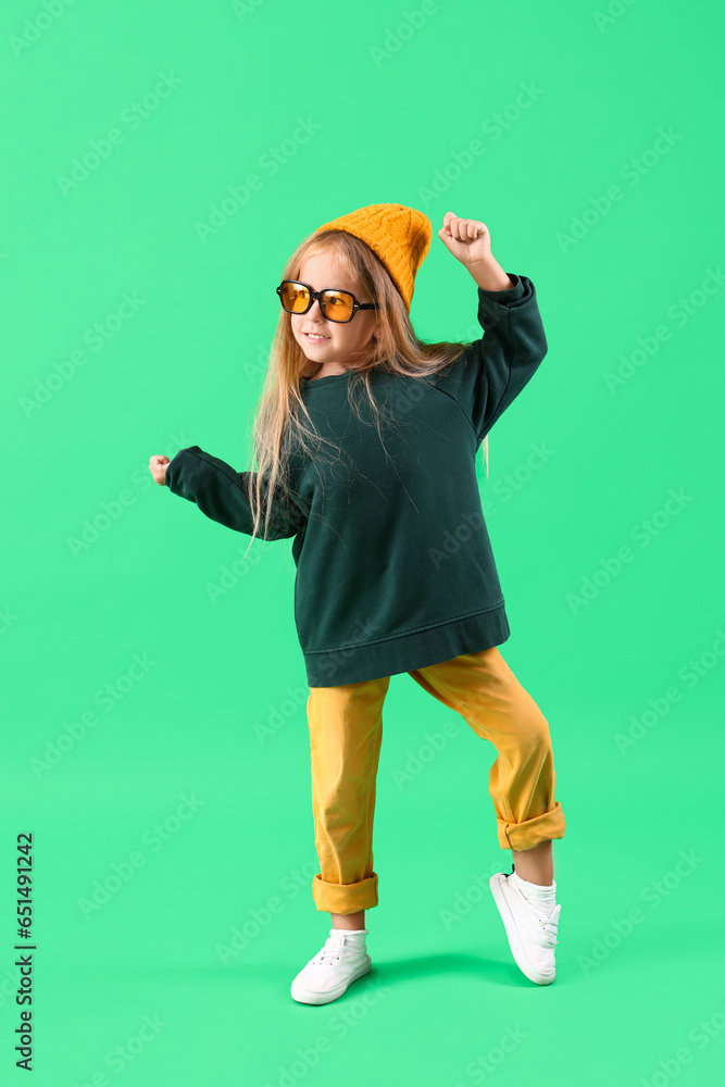Cute little girl dancing on green background