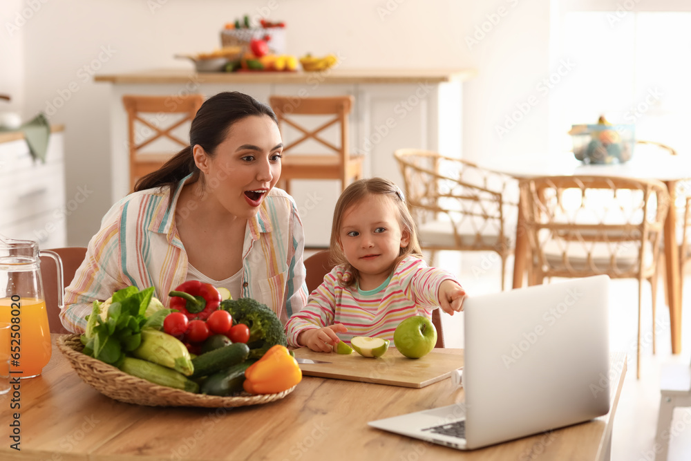Little girl with her mother eating apples in kitchen