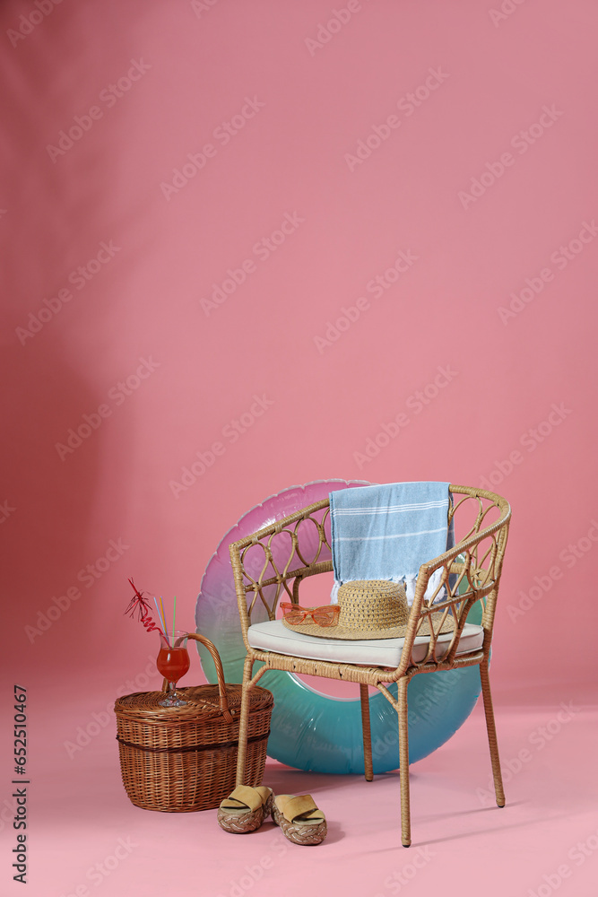 Composition with chair, wicker basket, beach accessories and cocktail on pink background. Travel concept