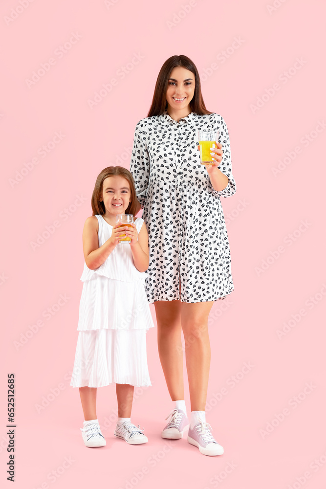 Little girl with her mother and glasses of juice on color background