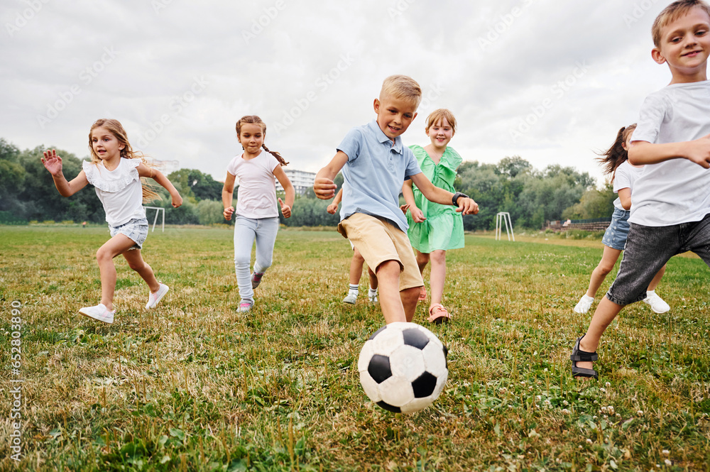 Soccer ball, playing together. Kids are having fun on the field at daytime
