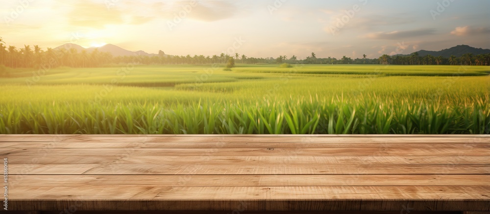 Empty wooden board on table with paddy field and sunrise background perfect for displaying products