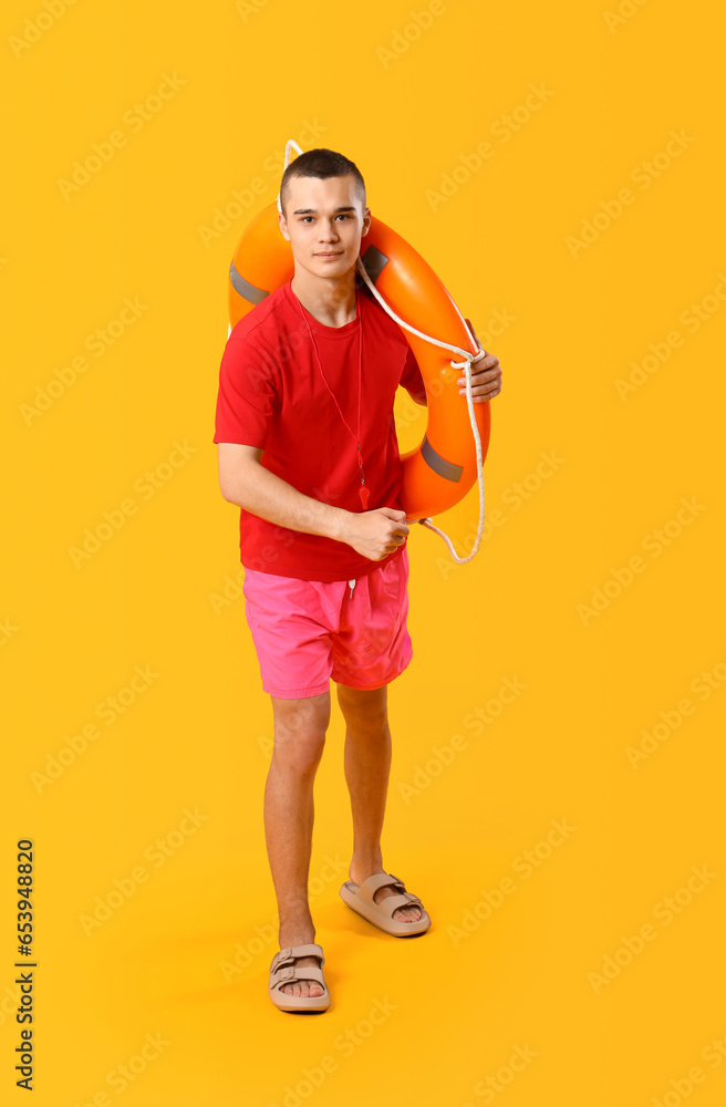 Male lifeguard with ring buoy on yellow background