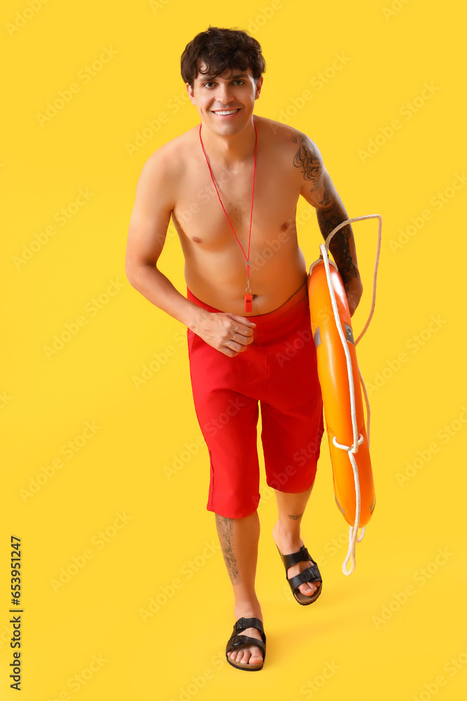 Male lifeguard with ring buoy running on yellow background