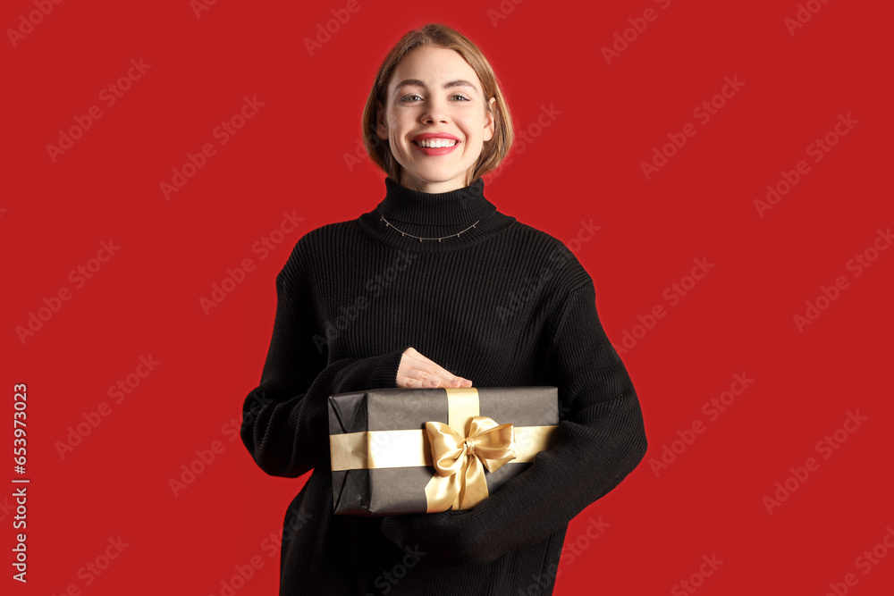 Young woman with gift on red background. Black Friday sale