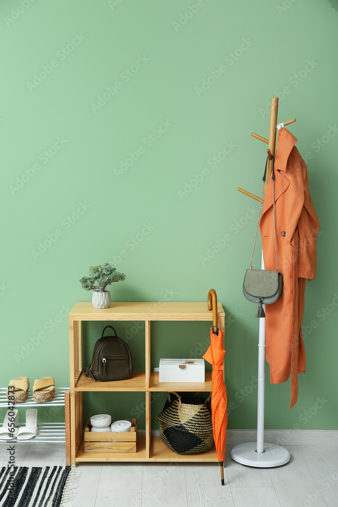 Shelving unit and stand with shoes near green wall in hall
