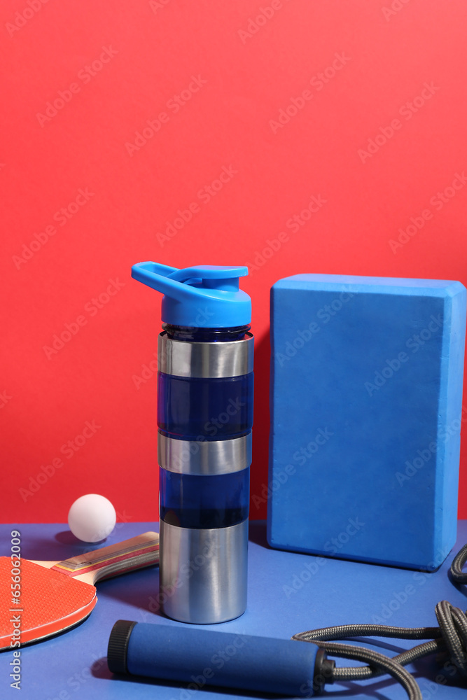 Bottle of water and different sports equipment on color background