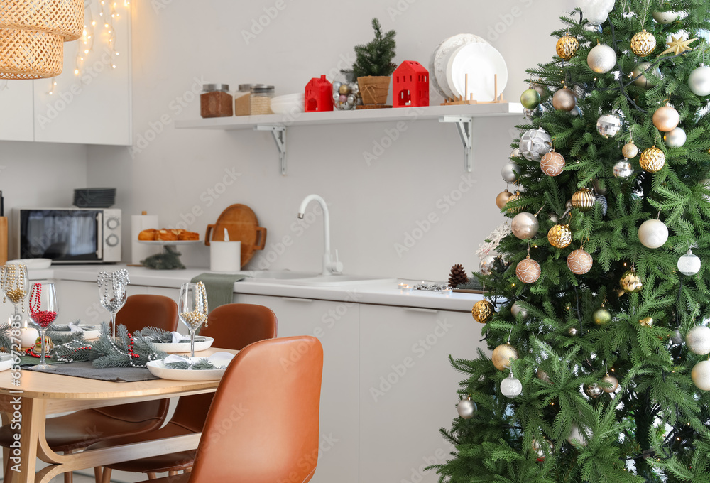 Interior of festive kitchen with Christmas tree and served dining table