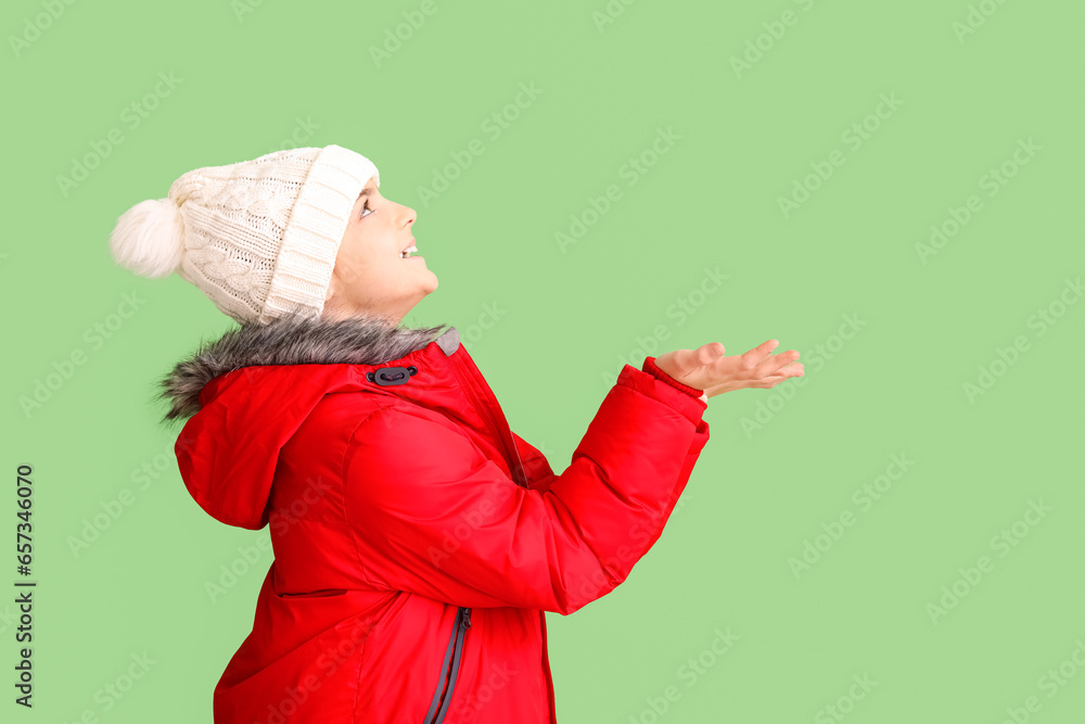Cute little girl in hat and warm down jacket on green background