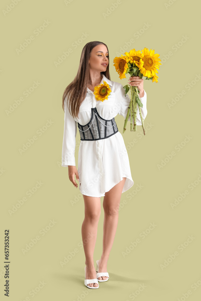 Young woman with bouquet of beautiful sunflowers on green background