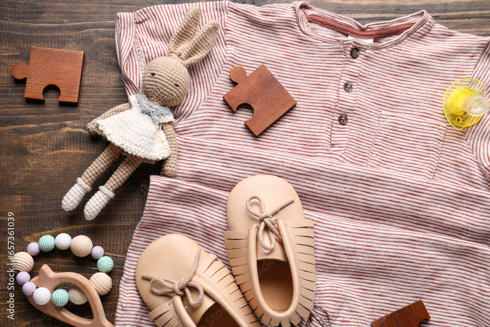 Composition with stylish baby bodysuit and accessories on wooden background, closeup
