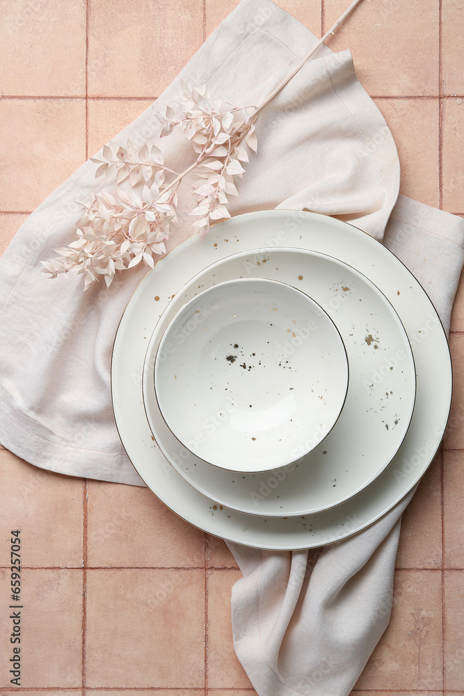 Clean white plates and bowl with floral decor on pink tiled table