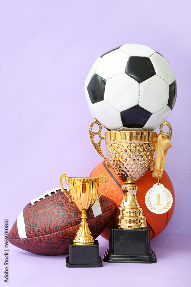 Gold cups with first place medal and balls on lilac background
