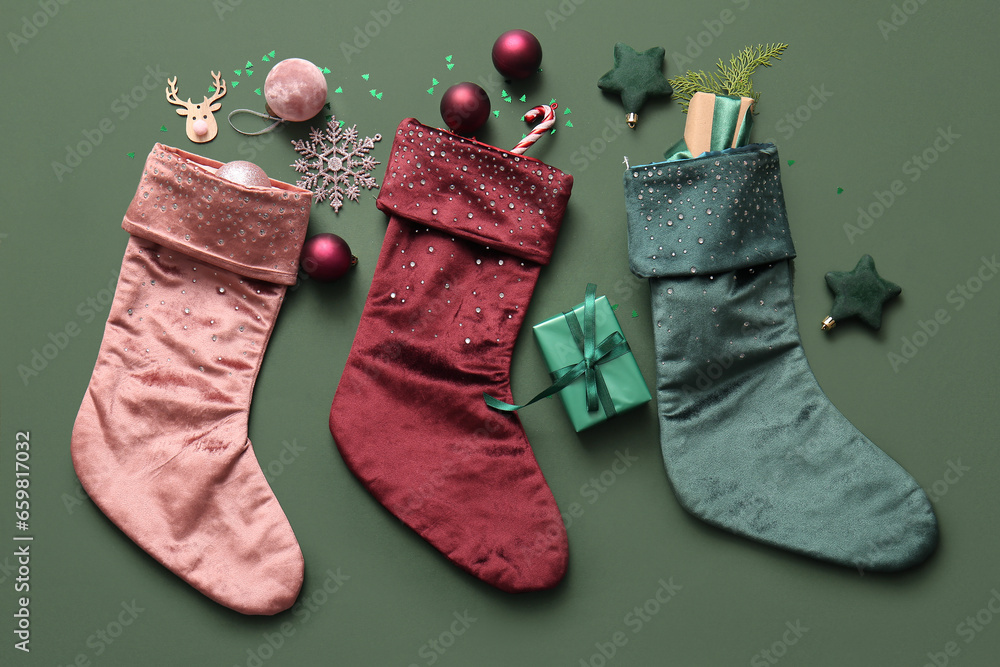 Beautiful Christmas socks with gift boxes and decorations on green background